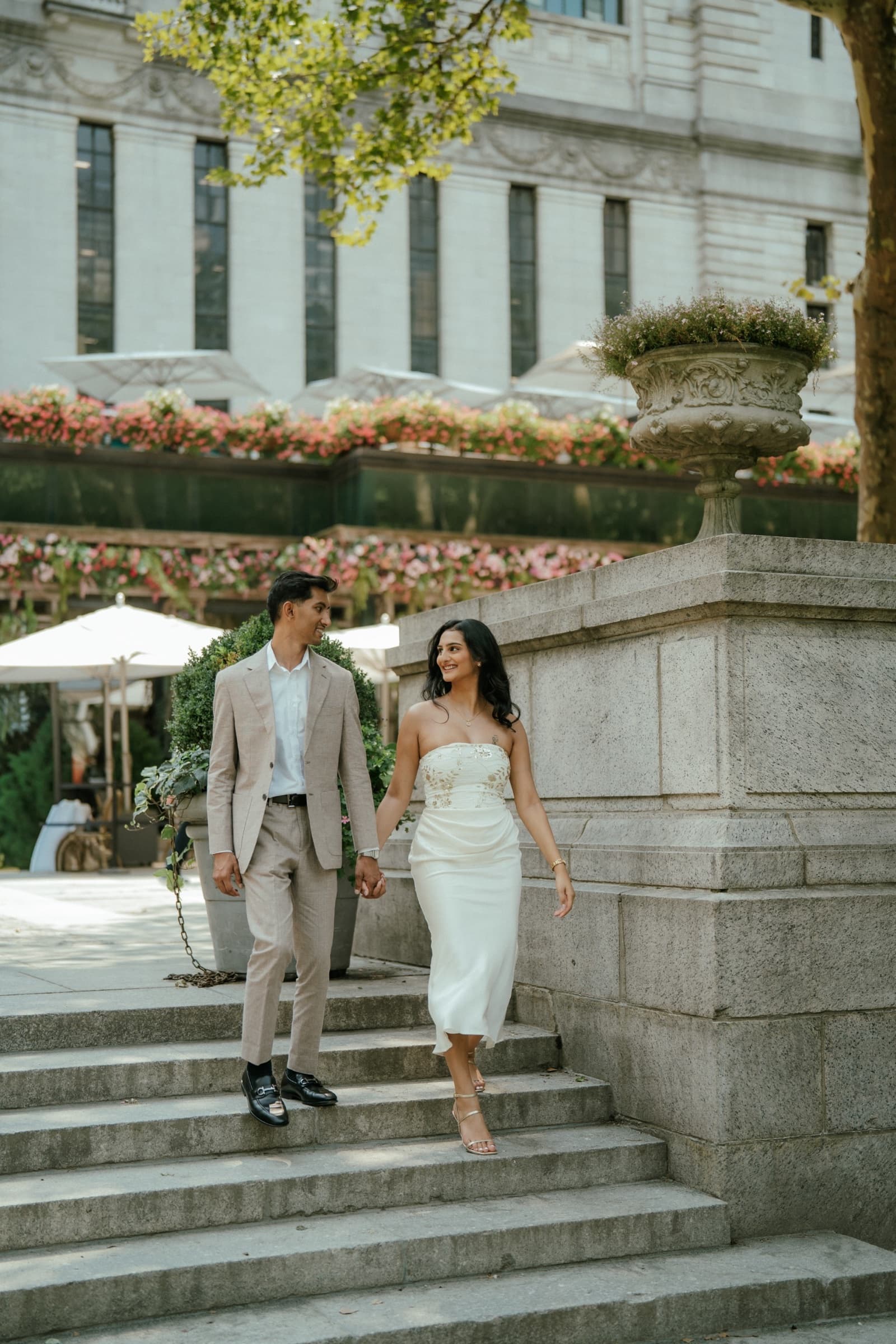 Ananya and Varun walking hand in hand through a garden courtyard